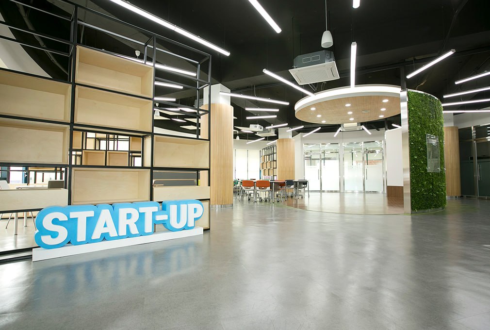 벤처스튜디오 창업 라운지 — START-UP 사인이 놓인 개방형 공간